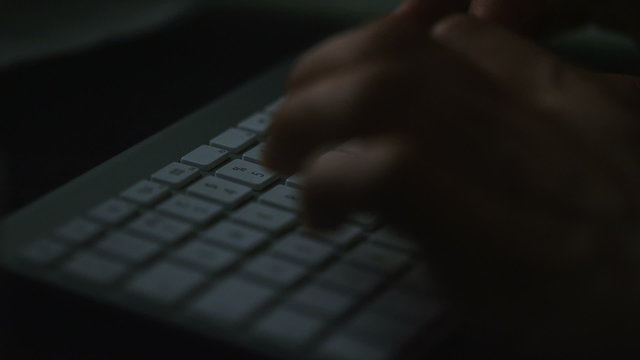 Hands typing on a keyboard at night