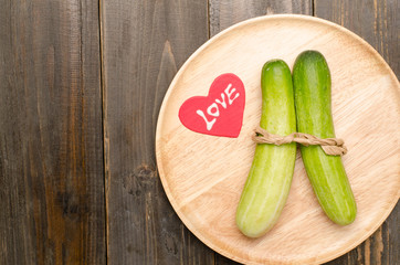 Fresh cucumber with love on wooden plate