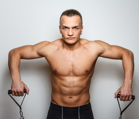 Muscular man doing exercises with expander
