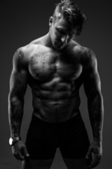 Muscular man with tattooes in deep shadows