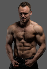 Fototapeta na wymiar Muscular man posing in studio on grey background