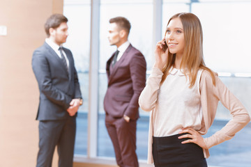 Blond young business woman standing in front of two men talking 