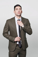 Handsome man in grey suit adjusting his tie