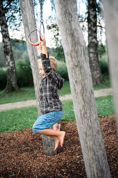 Junge schwingt mit Ringen am Spielplatz 