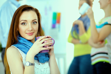 Portrait of attractive female  designer sittin on desk  in