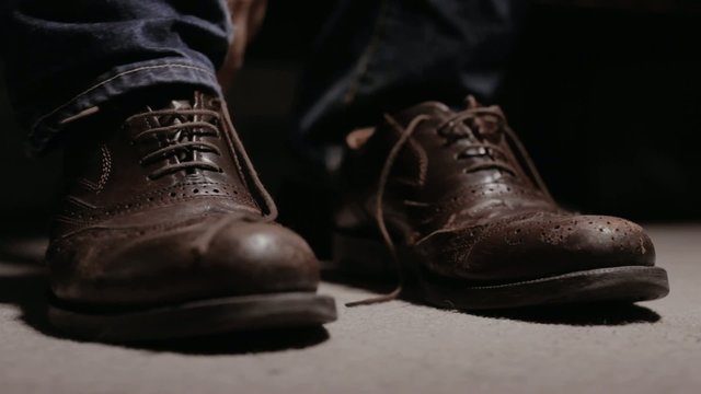 Man putting on a pair of shoes and tying his laces 