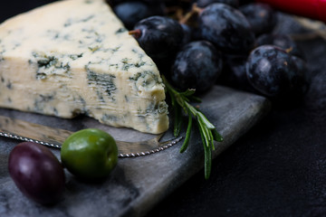 Marble board with cheese selection, wine and grapes