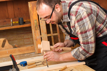 Closeup of a carpenter working with a chisel and carving tools in his workshop.