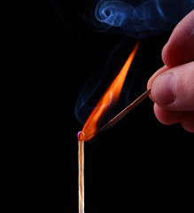 Ignition of a match, with smoke on dark background