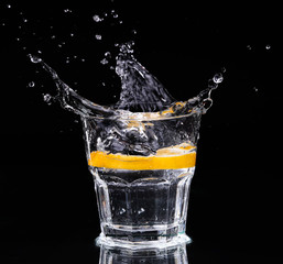 Slice of lemon splashing into a glass 