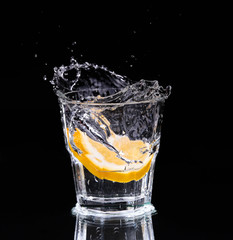 Slice of lemon splashing into a glass 