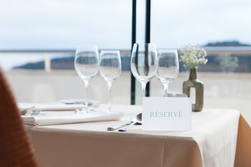 restaurant table by the window looking at sea - obrazy, fototapety, plakaty
