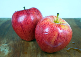 Two red apples on wooden background