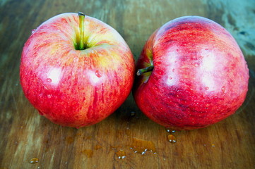 Two red apples on wooden board