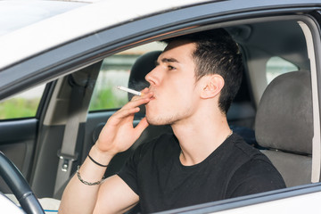 Young Man smoking cigarette while Driving