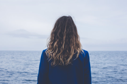 Blonde Curly Girl Looking At Hazy Sunshine Calm Sea Back View