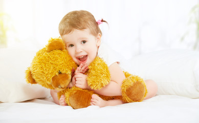 cute little child girl hugging teddy bear in bed