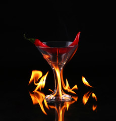 Hot chili pepper in a martini glass with a fire 
