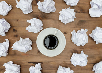 Cup of coffee paper sheets  and crumpled wads on table