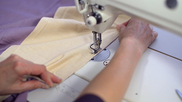 Female hands sewing on professional sewing machine.