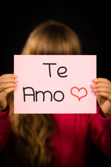 Child holding sign with Spanish words Te Amo - I Love You
