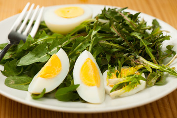 Fresh spring green  dandelion salad with eggs on a plate closeup
