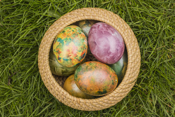 Tie-dyed Easter Eggs in Wicker Basket in gras