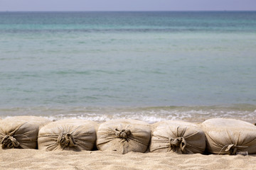 Fototapeta na wymiar Sacchi di sabbia su sfondo mare