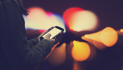 Typing messages - with defocused city lights.