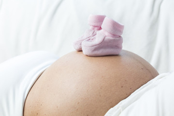 Schwangere Frau Detail Bauch mit Babyschuhen