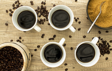 4 Black coffee cup with beans and sugar on wooden surface from a