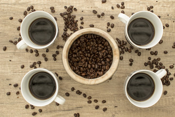4 Black coffee cup with beans on wooden surface from above