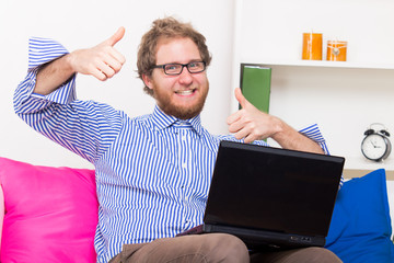 Happy man shows OK sign in front of a computer - obrazy, fototapety, plakaty