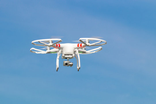 Drohne mit  Kamera schwebt vor blauem Himmel