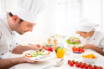 Young attractive professional chef cooking in his kitchen