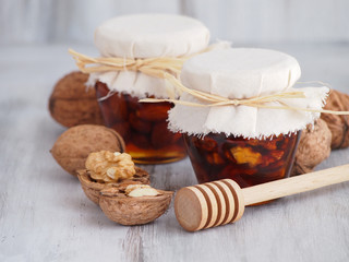 Fototapeta na wymiar Walnuts, almonds and honey in jars and honey dipper