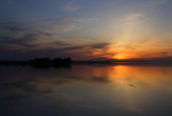 Fototapeta na wymiar sunset on a river, sun over island on a lake