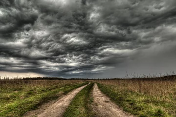 Abwaschbare Fototapete dirt road going into the eye of the storm. © manyasha