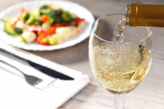 Pouring white wine and salad