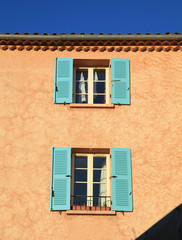 orange rural house with open windows and blue shutters, Provence