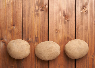 Three potatoes over the wooden surface