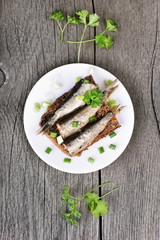 Sprats sandwich with herbs on rustic table