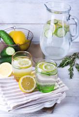 Fresh water with lemon and cucumber in glassware on wooden background