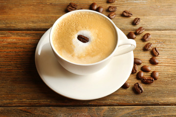 Cup of latte art coffee with grains on wooden background