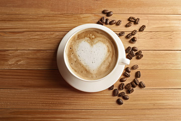Cup of coffee latte art with grains on wooden table, top view