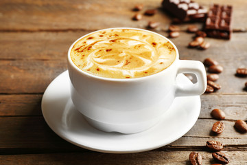 Cup of coffee latte art with grains and chocolate on wooden background