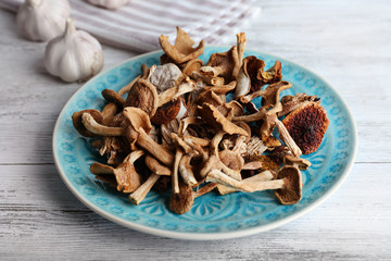 Dried mushrooms in plate on wooden table, closeup