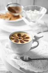 Cup of latte coffee art on wooden table, on light background