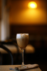 Glass of coffee with cream on table in cafe