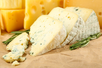 Various types of cheese with rosemary on table close up